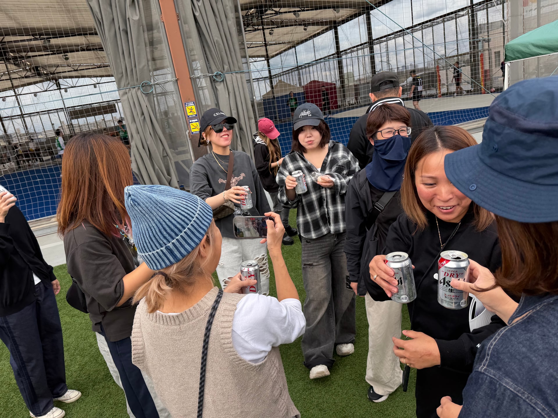 缶ビールを手に笑顔で歓談・撮影している様子