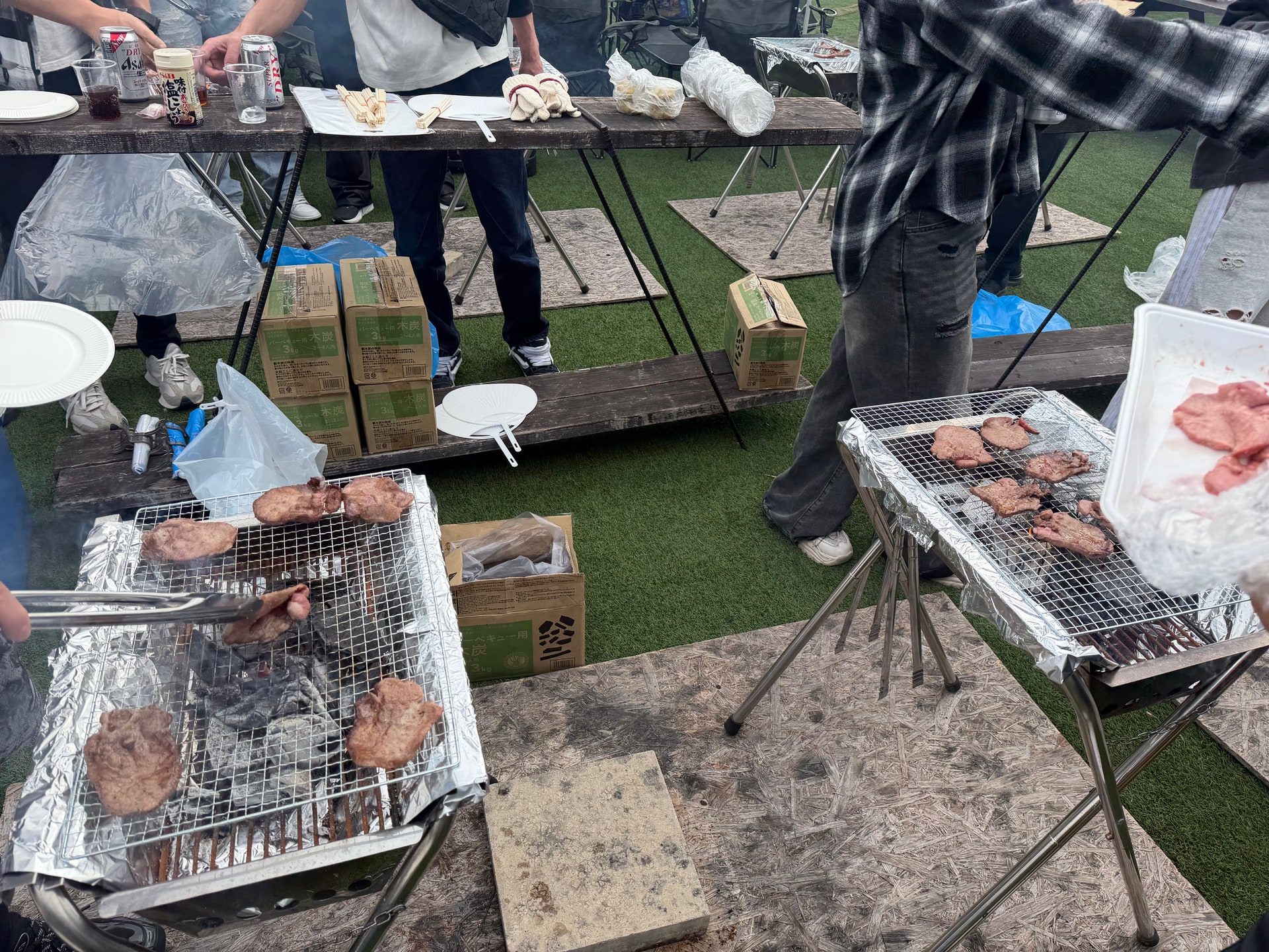 炭火グリルで肉をトングでさばいている様子
