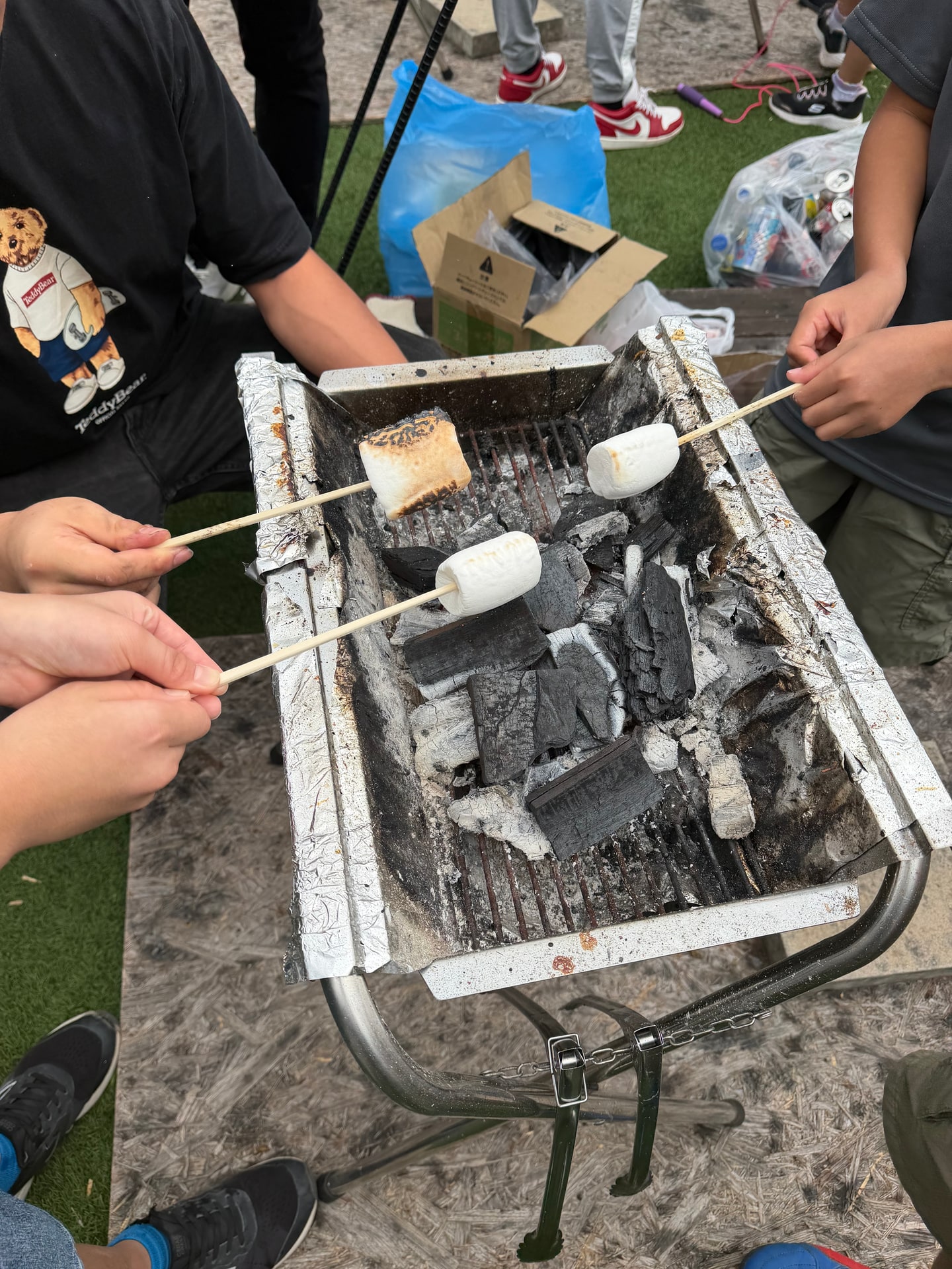 炭火の上に竹串でマシュマロを焼いている様子