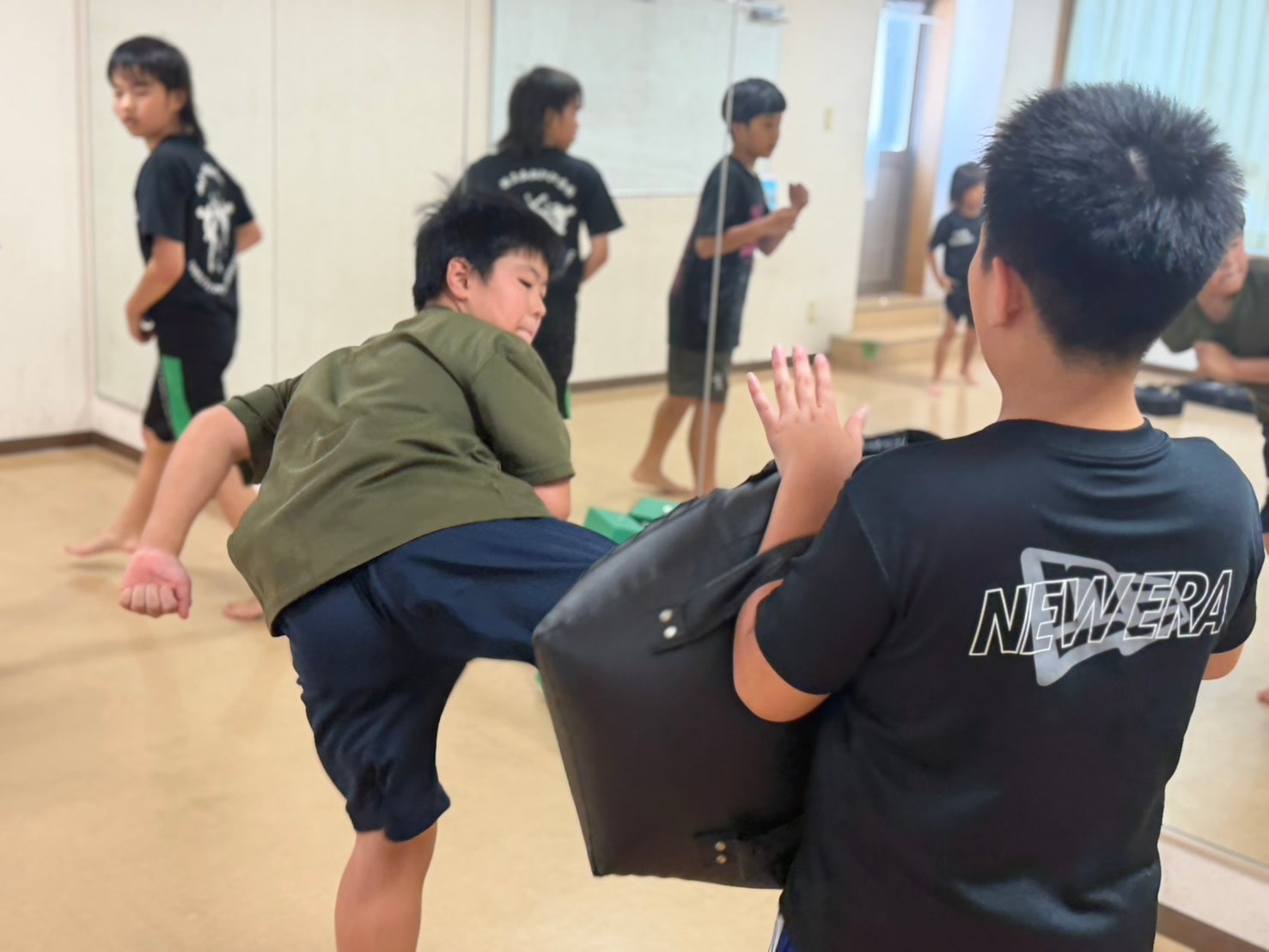 ミット稽古で蹴りを打ち込む生徒」 class=