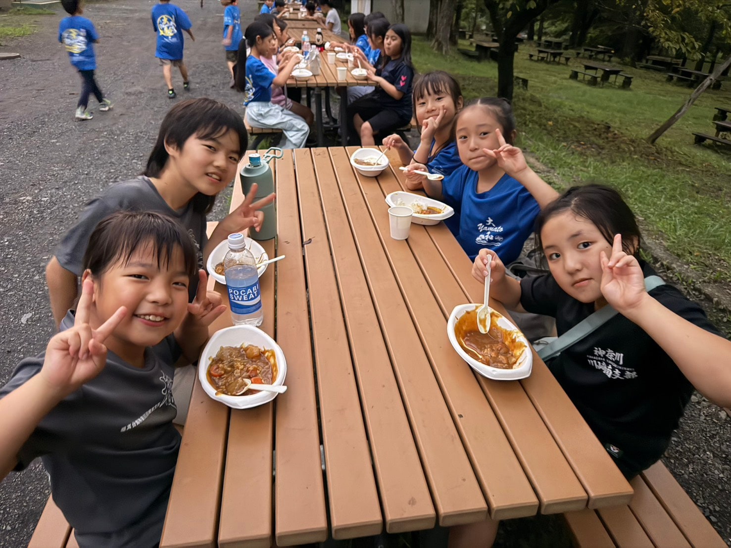 手作りカレーを食べながら笑顔でピースする子供たち」loading=