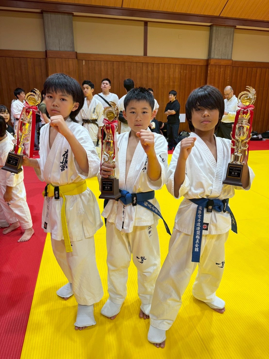 川崎南D 小学4〜6年 初級チャレンジ団体 優勝メンバー3名がトロフィーを持ち構えをとる様子