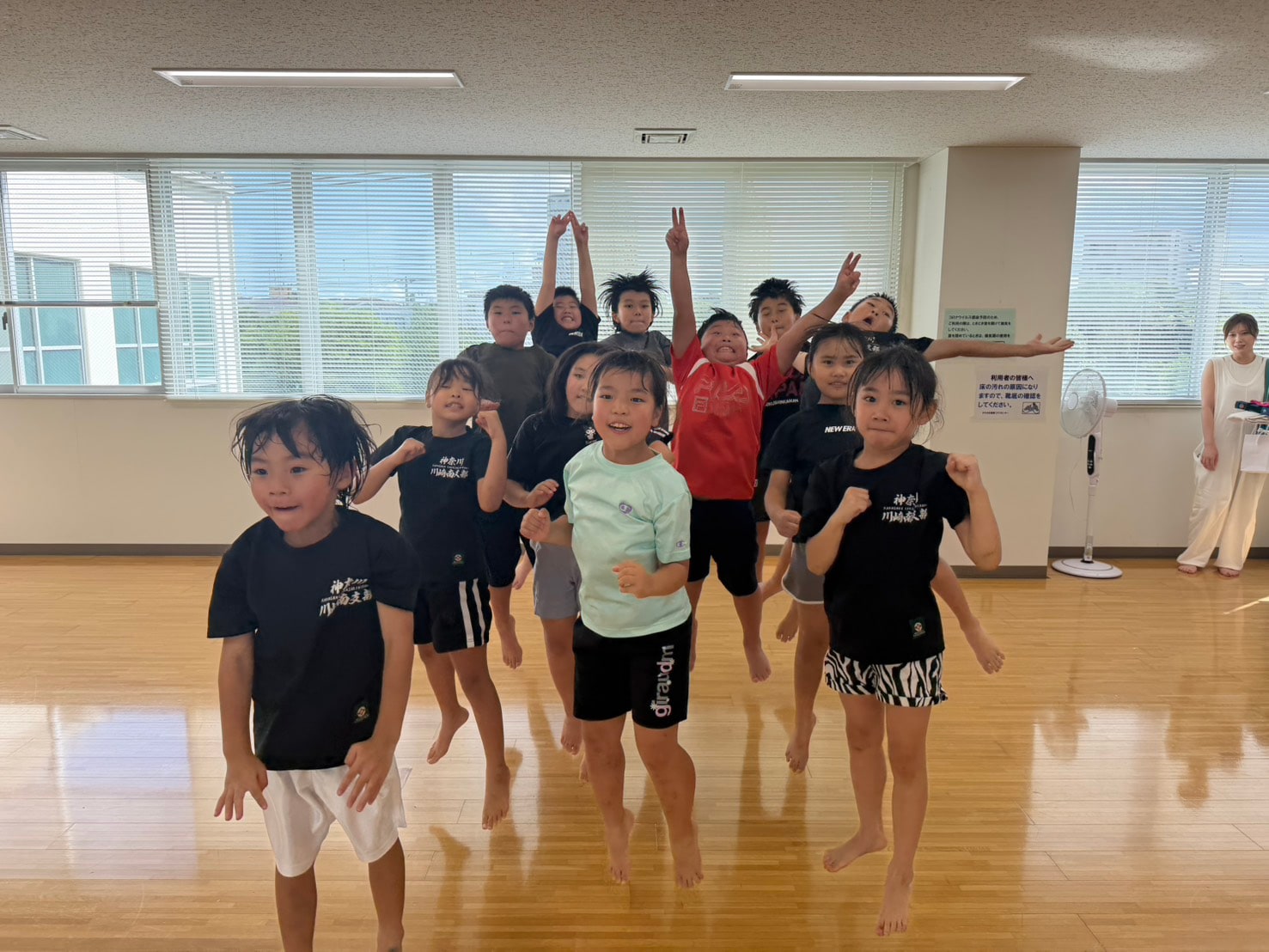 元気よくポーズを決める選手クラスの子どもたちと笑顔の指導員