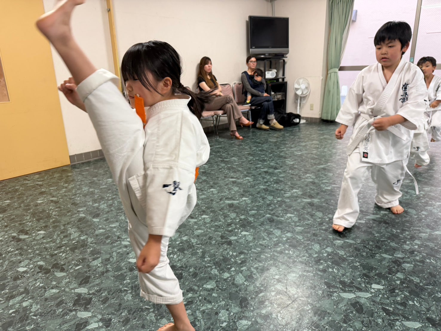 蹴り技の動作を見せる道場生と仲間たち