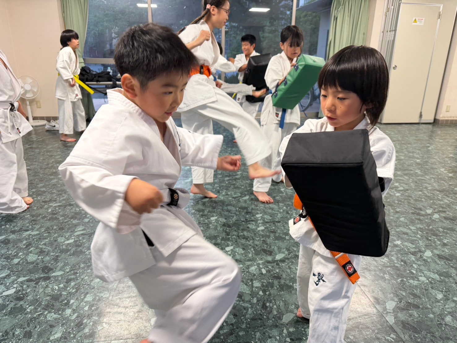 ミット打ちで蹴りを打ち込む道場生