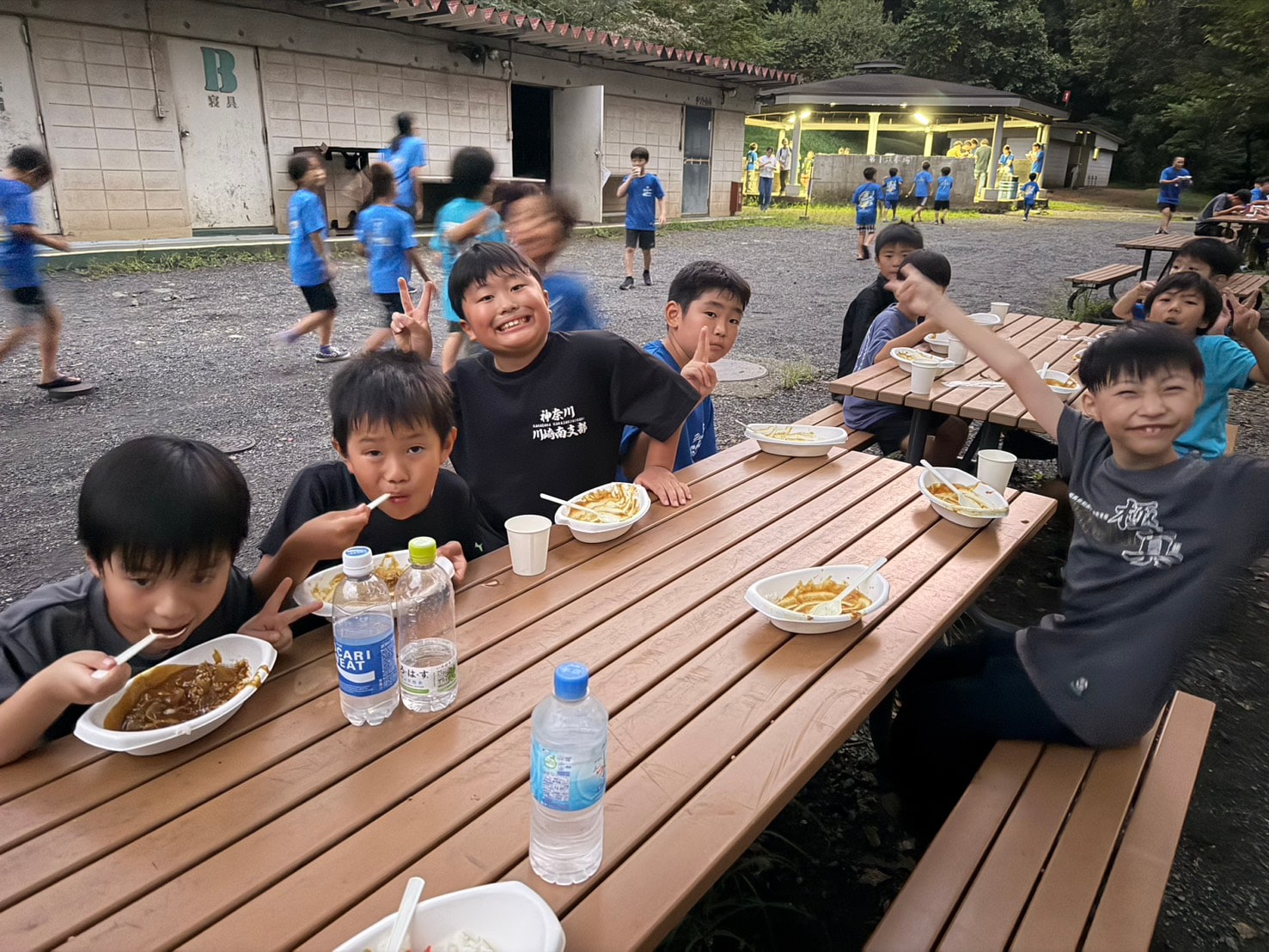 屋外テーブルでカレーを食べる子供たち