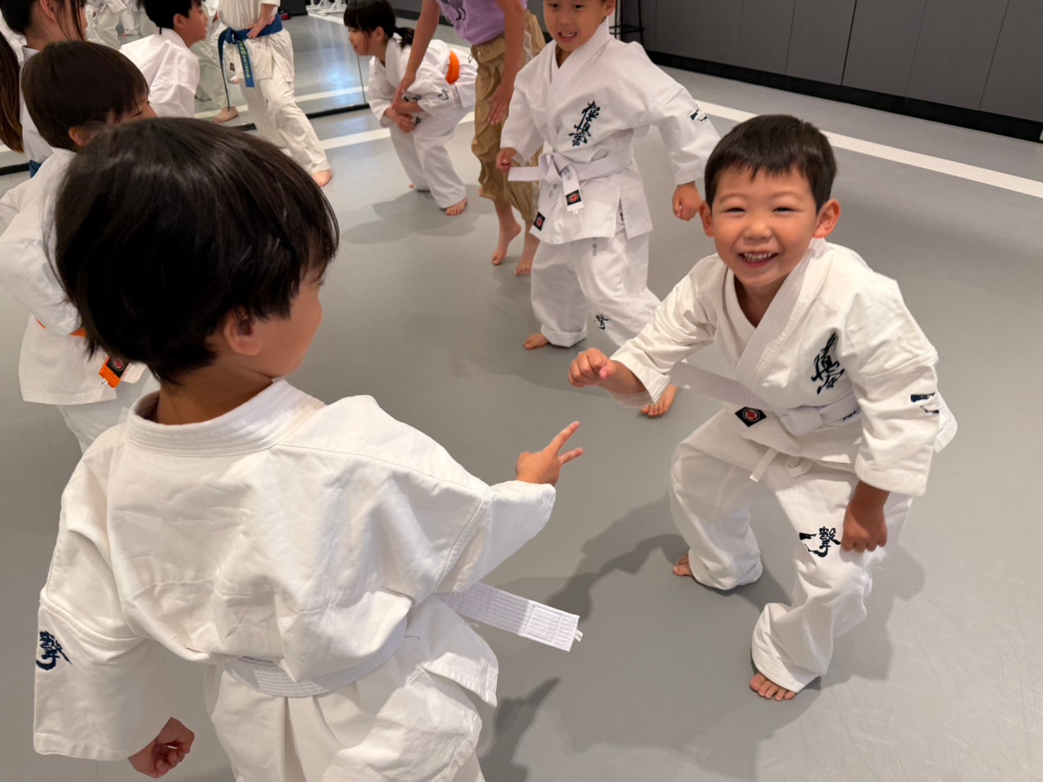 白帯の子どもたちが笑顔で稽古する様子