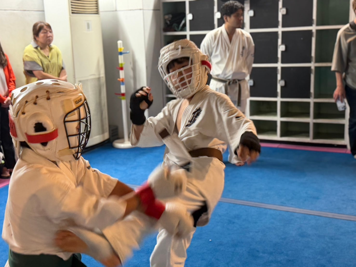 子ども2人が防具をつけて真剣に組手スパーリングをしている