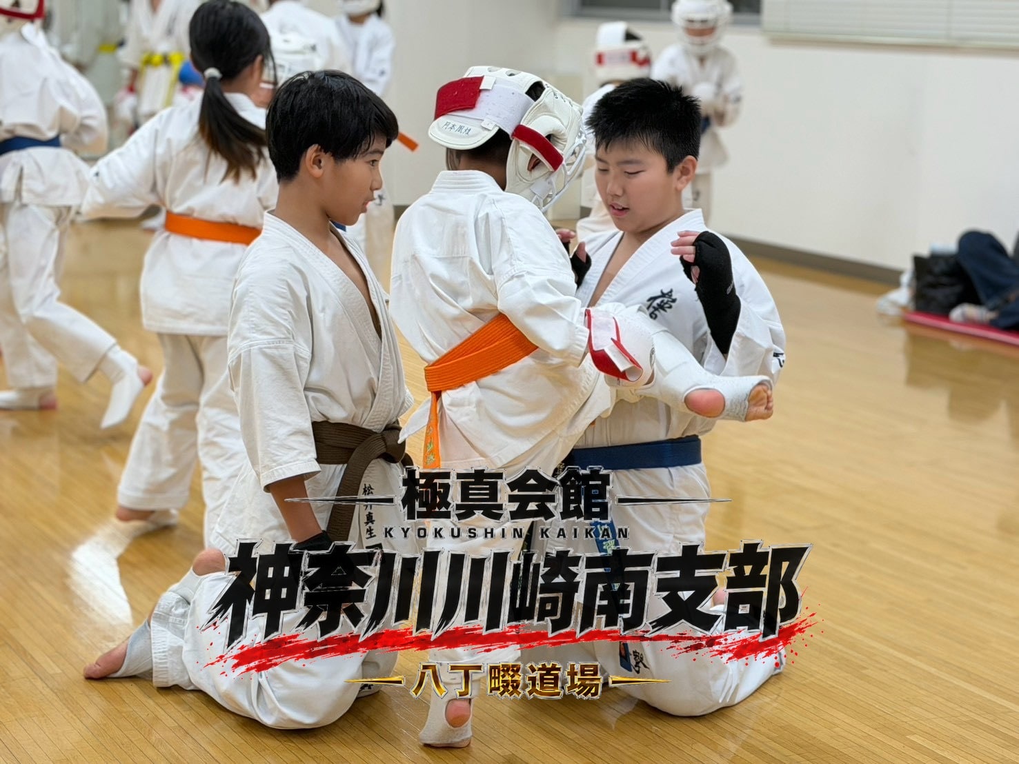 先輩が後輩に膝立ちで丁寧に技を教えている場面