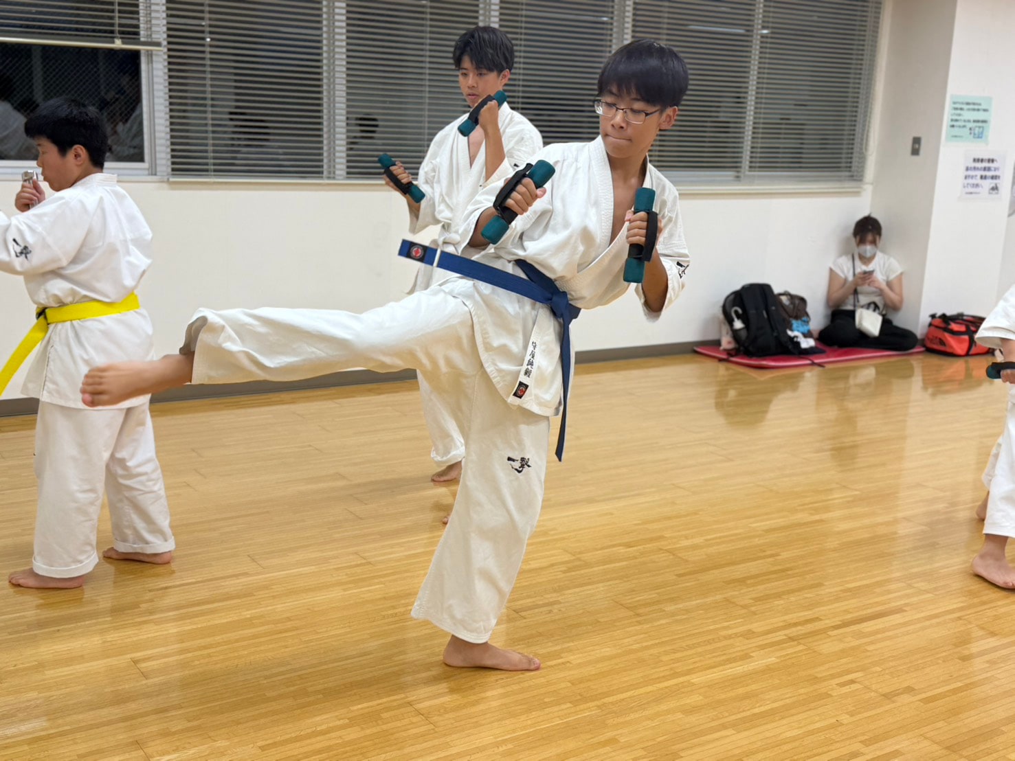 蹴りを織り交ぜながらダンベル稽古をする道場生」loading=