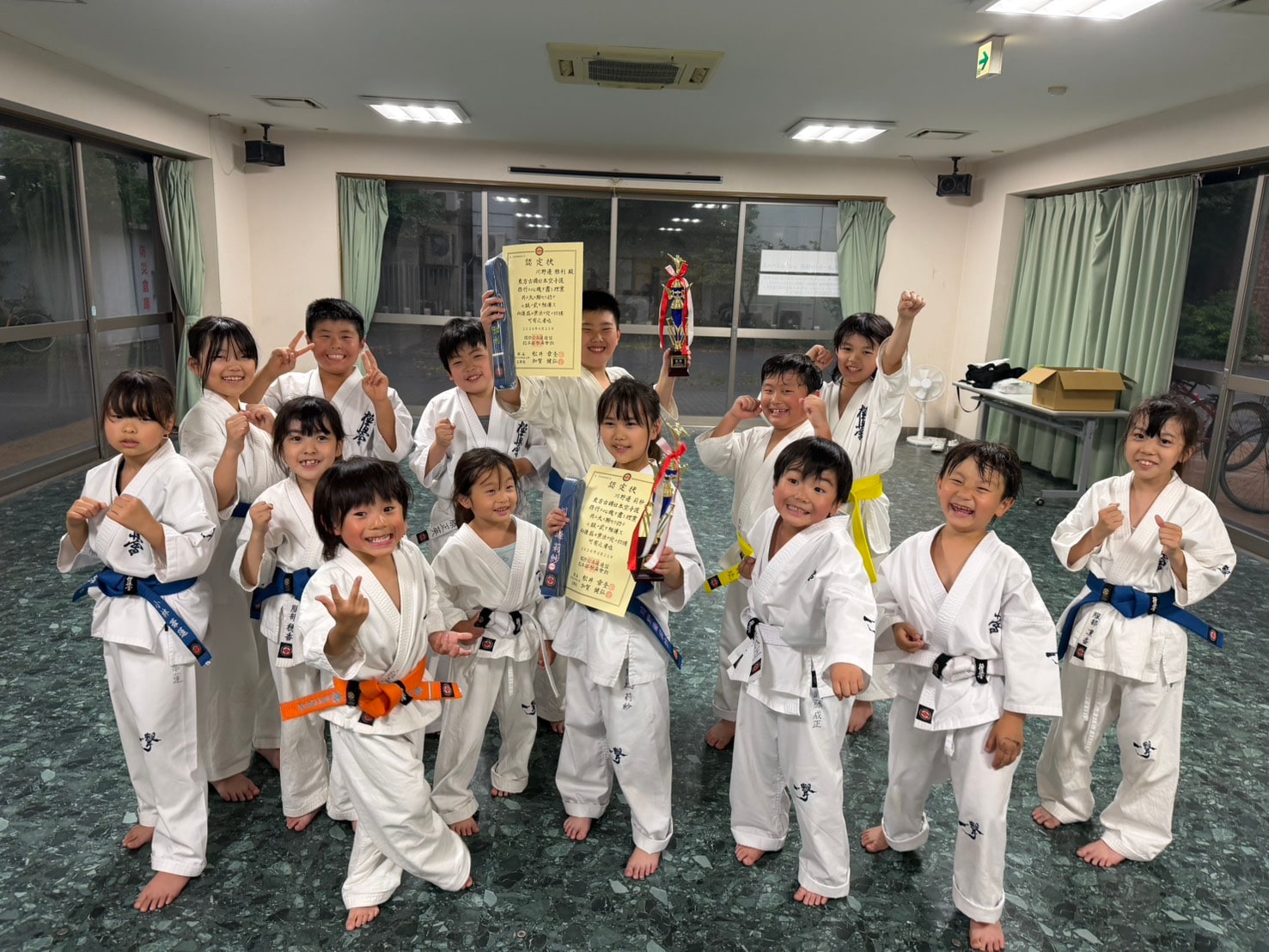 帯を手にして笑顔で記念撮影する少年クラスの生徒たち