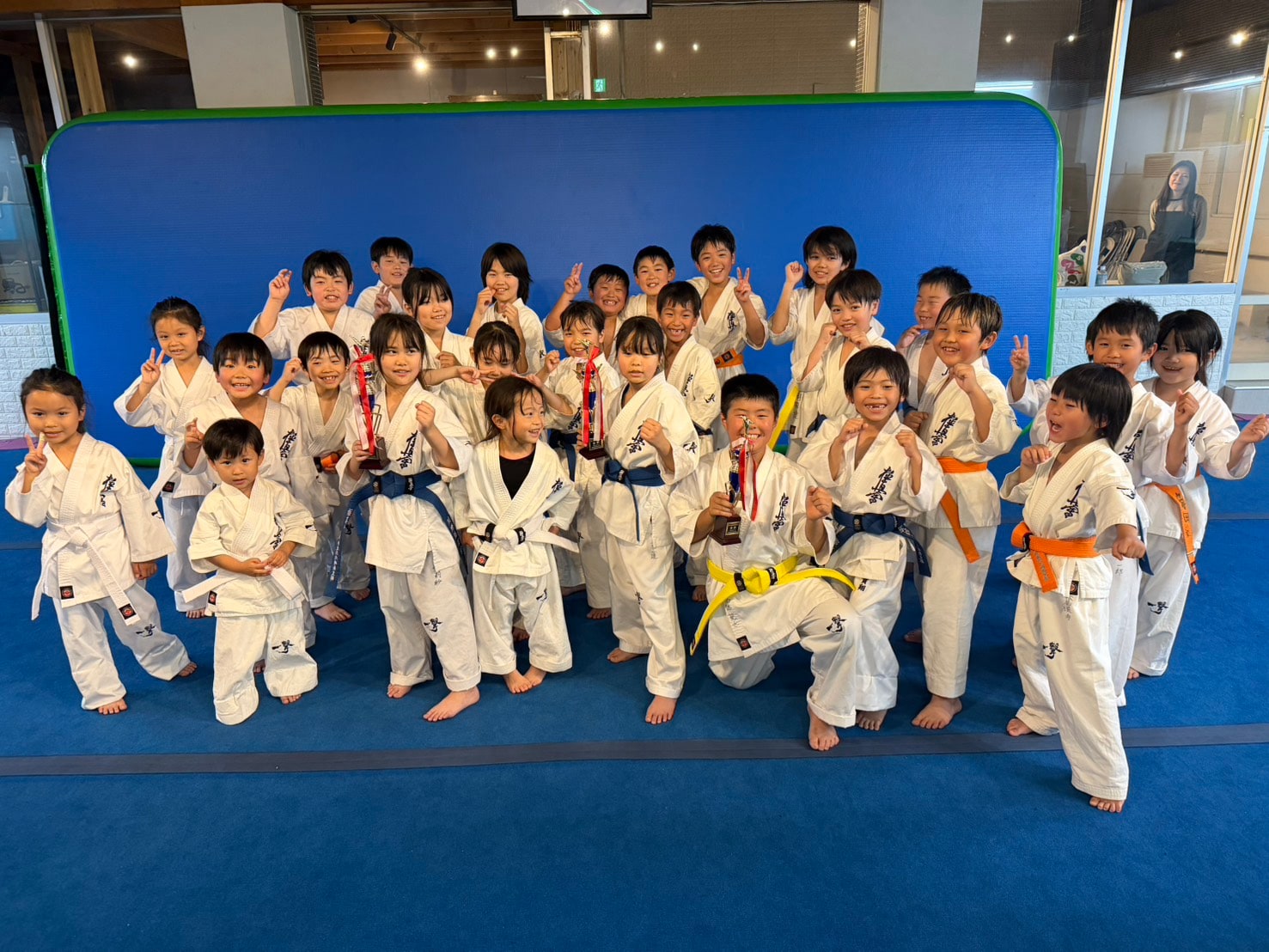 御幸道場の幼年少年クラスの生徒たちが型大会優勝トロフィーを持ってみんなで記念写真