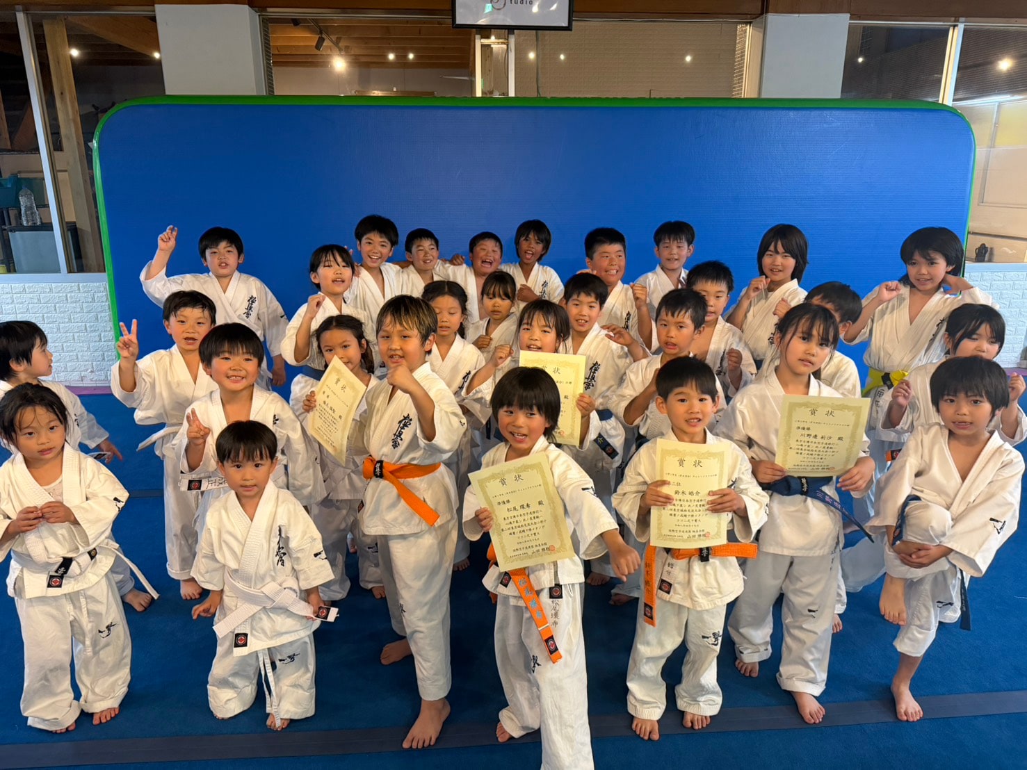 賞状を手に笑顔で集合する幼年・少年道場生の全員写真」